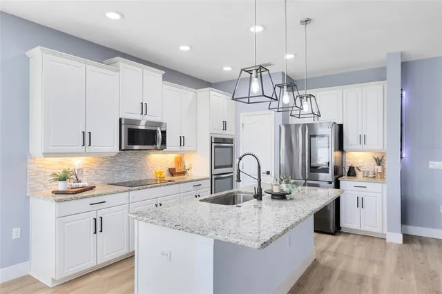 a kitchen with stainless steel appliances granite countertop a sink a stove and a wooden floors