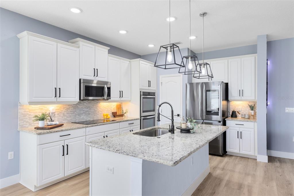 1048 Fountain Coin Loop Orlando, FL 32828 - Photo 3 of 39 a kitchen with stainless steel appliances granite countertop a sink a stove and a wooden floors