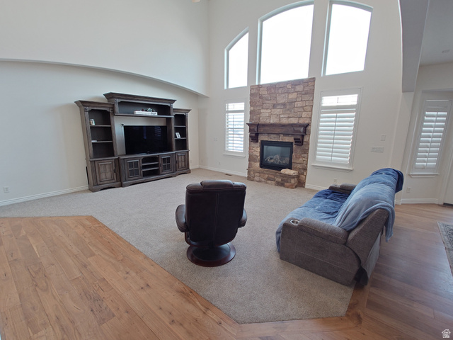 552 Sunset Crest Way Draper, UT 84020 - Photo 14 of 68 Living room featuring a high ceiling, a stone fireplace, and light wood finished floors