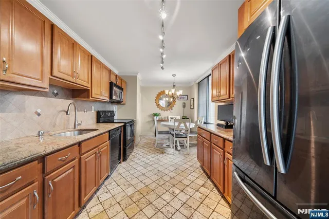 a kitchen with stainless steel appliances granite countertop a refrigerator a sink dishwasher a stove and white countertops with wooden floor