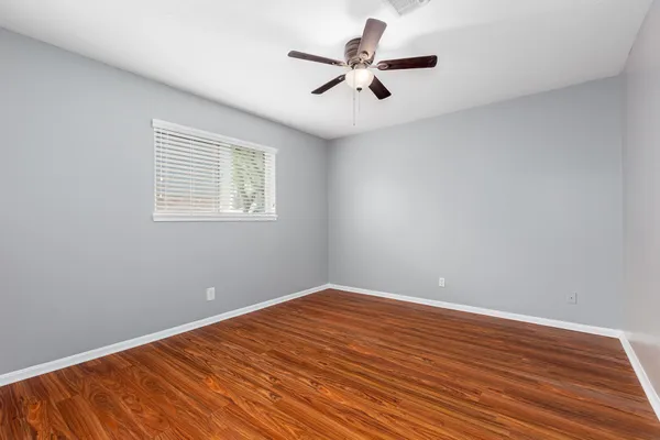 an empty room with wooden floor and windows