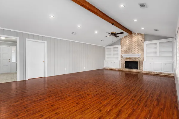 a view of empty room with wooden floor and fireplace