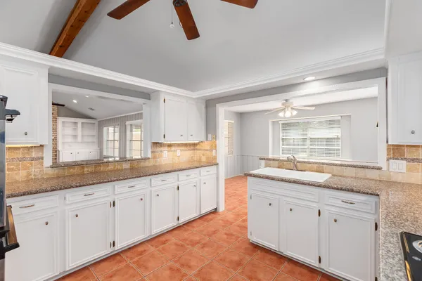 a kitchen with granite countertop white cabinets white appliances and a sink