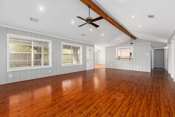 a view of an empty room with wooden floor and a window
