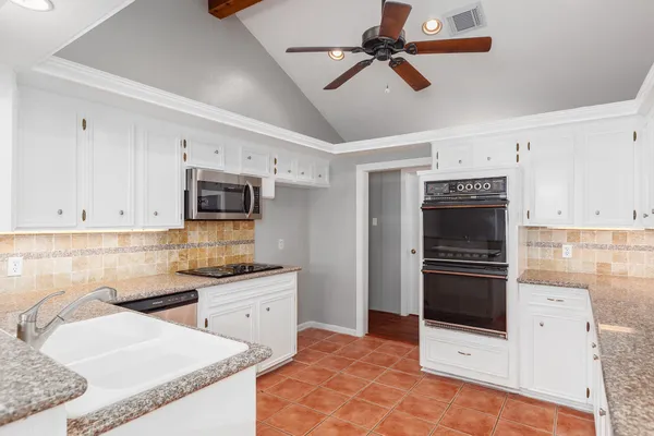 a kitchen with stainless steel appliances kitchen island granite countertop a sink stove and refrigerator