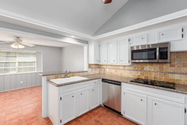 a kitchen with granite countertop white cabinets stainless steel appliances a sink and a window