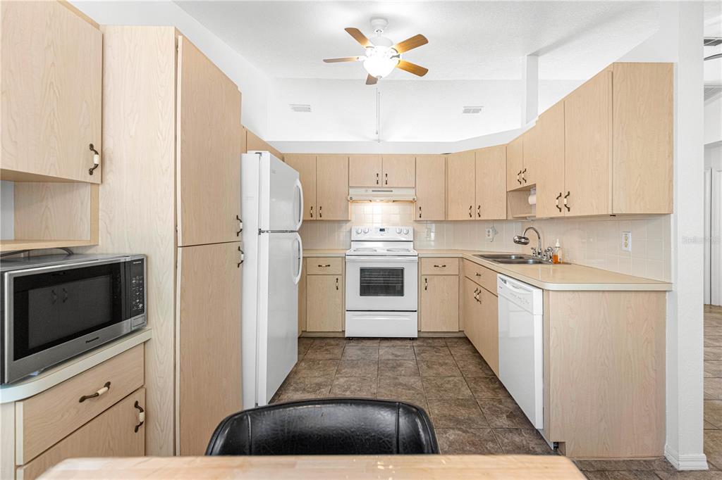 6115 Southwest 104th Street Ocala, FL 34476 - Photo 13 of 39 a kitchen with cabinets a sink and white stainless steel appliances