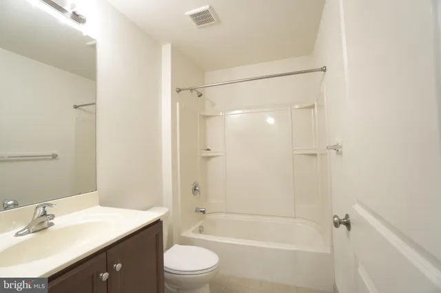 a bathroom with a bathtub shower sink vanity and toilet