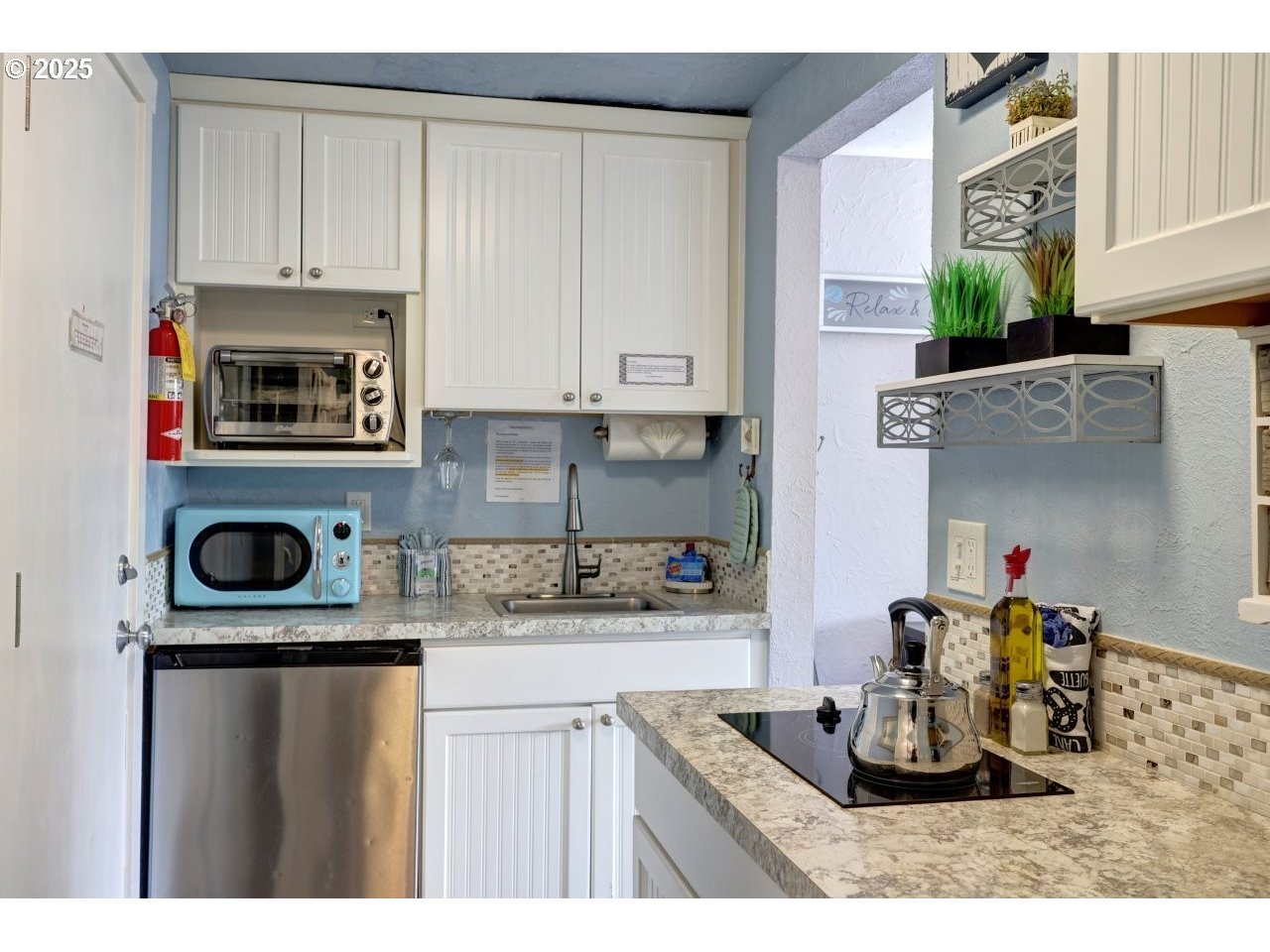 1022 North Prom Tradewinds, Unit 208 Seaside, OR 97138 - Photo 15 of 34 a kitchen with kitchen island granite countertop a stove a sink and a microwave