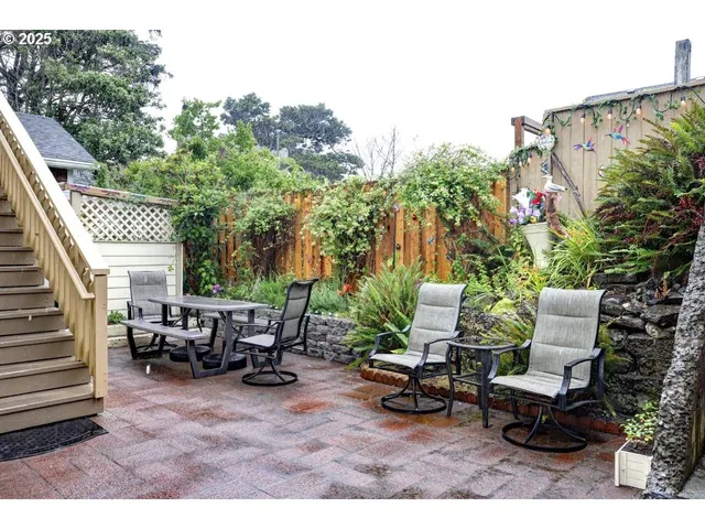 a view of a patio with table and chairs with wooden fence and plants