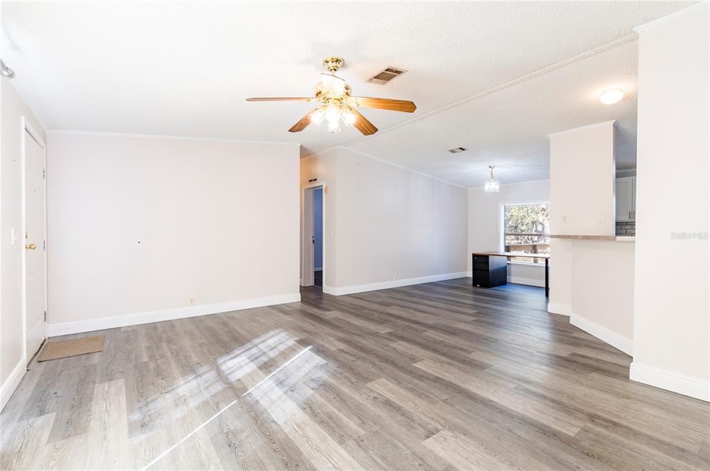 16314 Tiger Trail Spring Hill, FL 34610 - Photo 9 of 43 a view of an empty room and kitchen with wooden floor