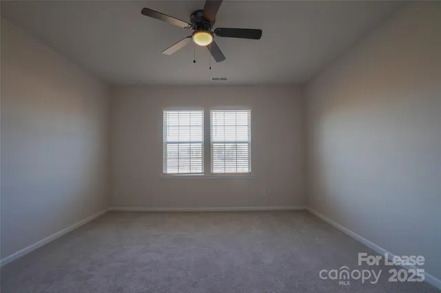 an empty room with a window and a ceiling fan