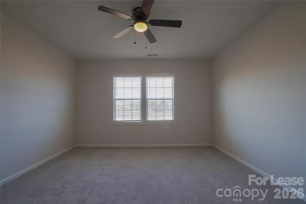 an empty room with a window and a ceiling fan