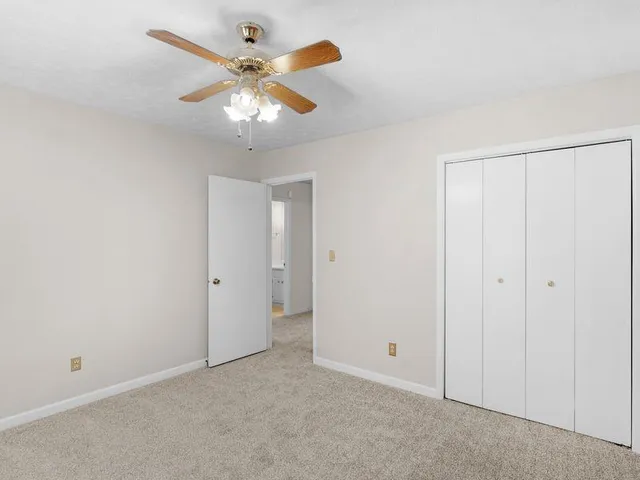 an empty room with closet and a chandelier fan