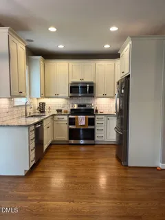 a kitchen with stainless steel appliances granite countertop a stove top oven a sink and a refrigerator