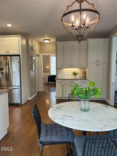 a kitchen with stainless steel appliances granite countertop a table chairs and a refrigerator