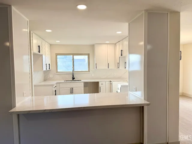 a room with stainless steel appliances granite countertop a dishwasher a stove a refrigerator and a dining table with wooden floor