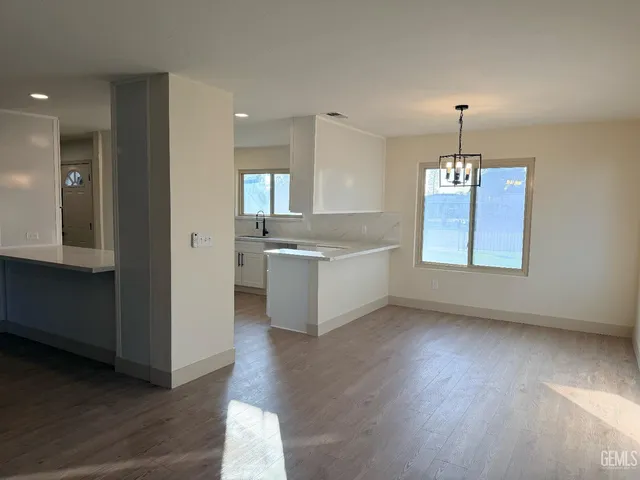 a view of an empty room with window and a kitchen