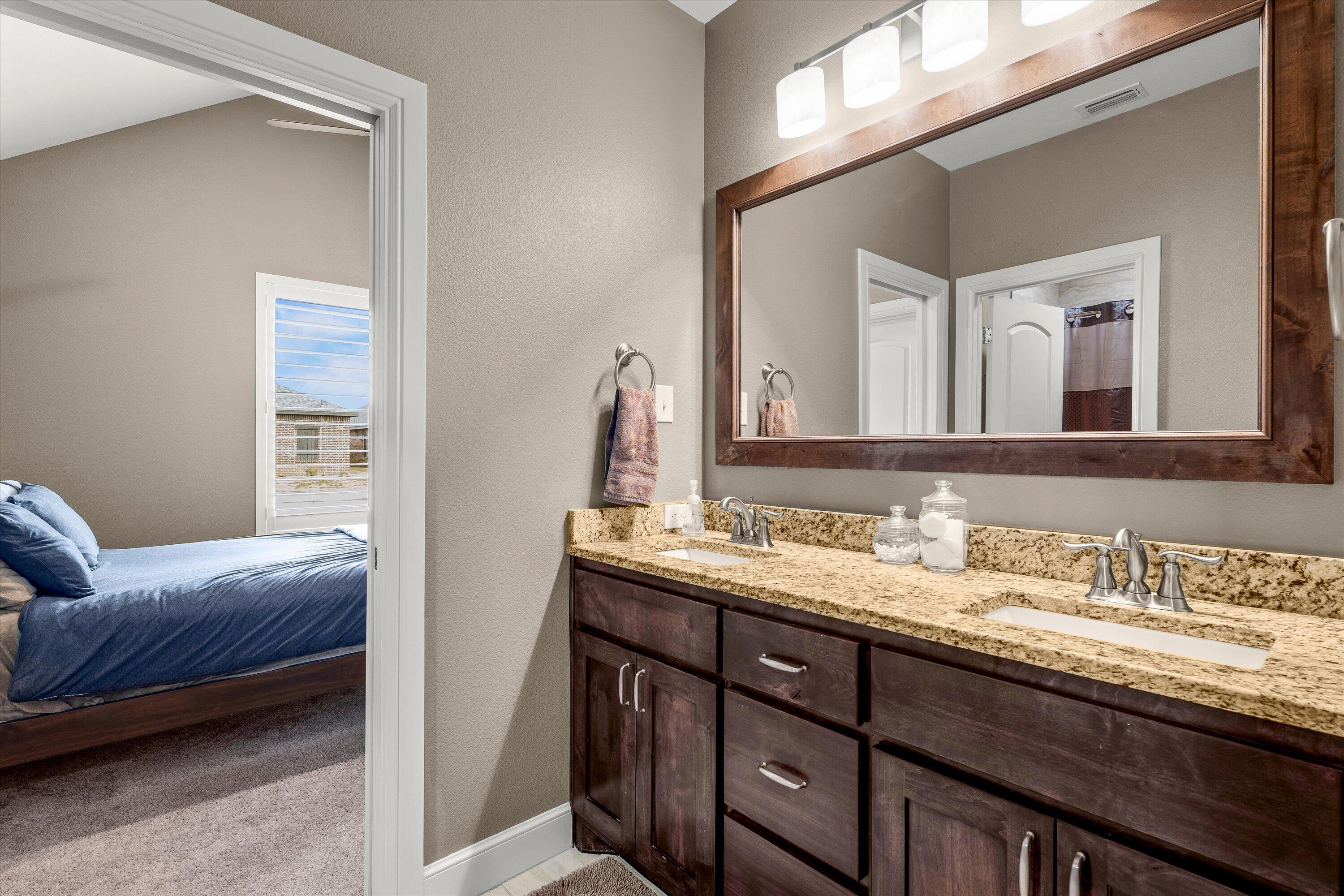 7033 101st Street Lubbock, TX 79424 - Photo 23 of 38 a en suite bathroom with a granite countertop sink and a mirror