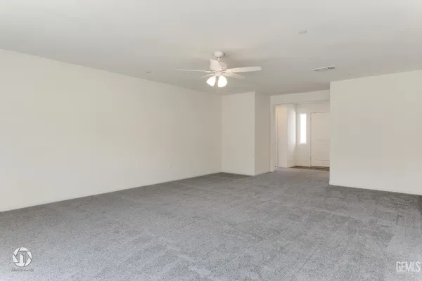 an empty room with chandelier fan and windows
