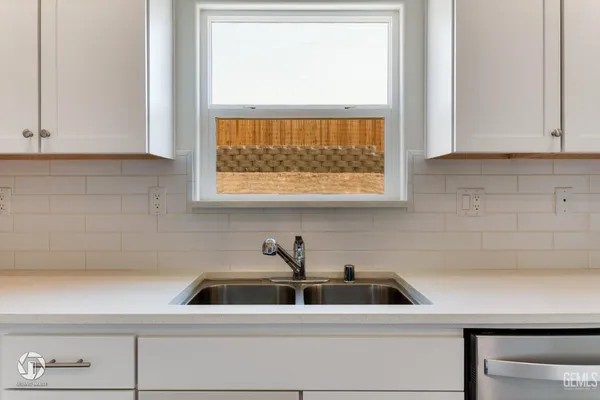 a kitchen with white cabinets and sink