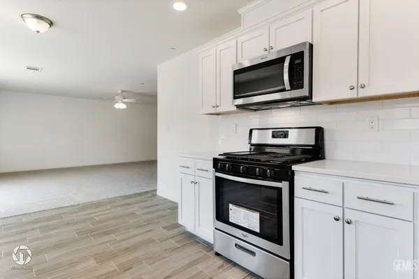 a kitchen with stainless steel appliances white cabinets and a stove top oven