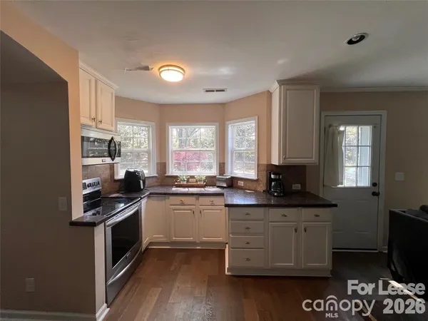 a kitchen with stainless steel appliances granite countertop a stove a sink and a microwave