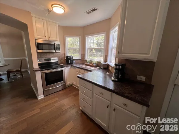 a kitchen with granite countertop a stove a sink and a microwave