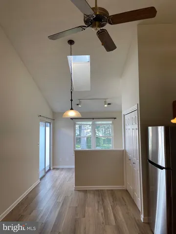 a view of a kitchen with a refrigerator a ceiling fan and wooden floor