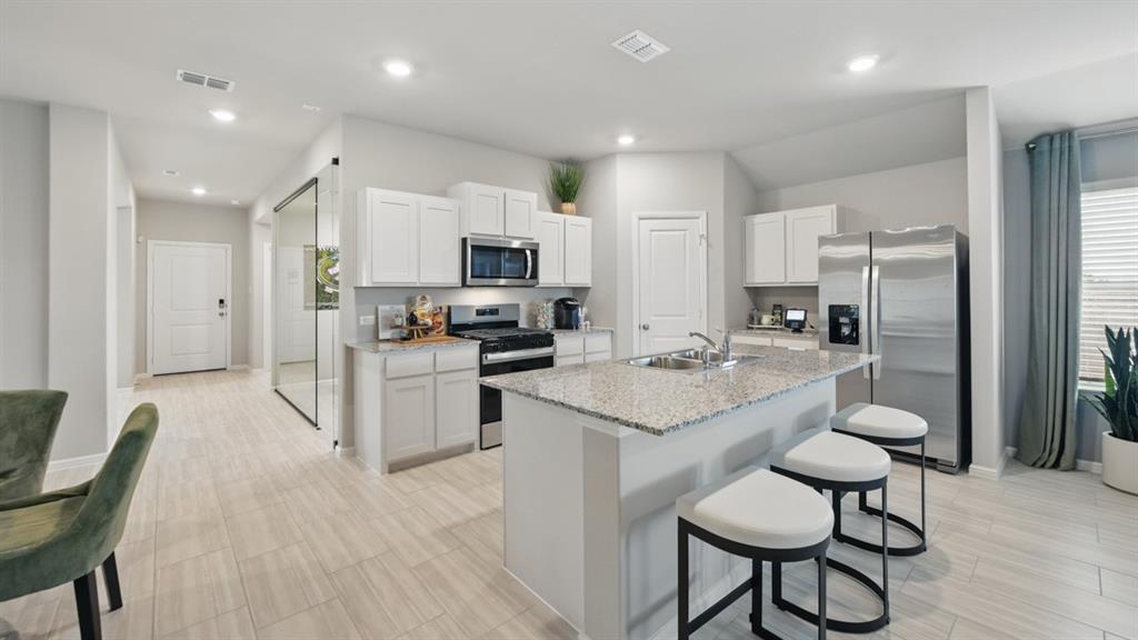 5545 Legends Way Krum, TX 76249 - Photo 34 of 36 a kitchen with kitchen island granite countertop a sink and stainless steel appliances