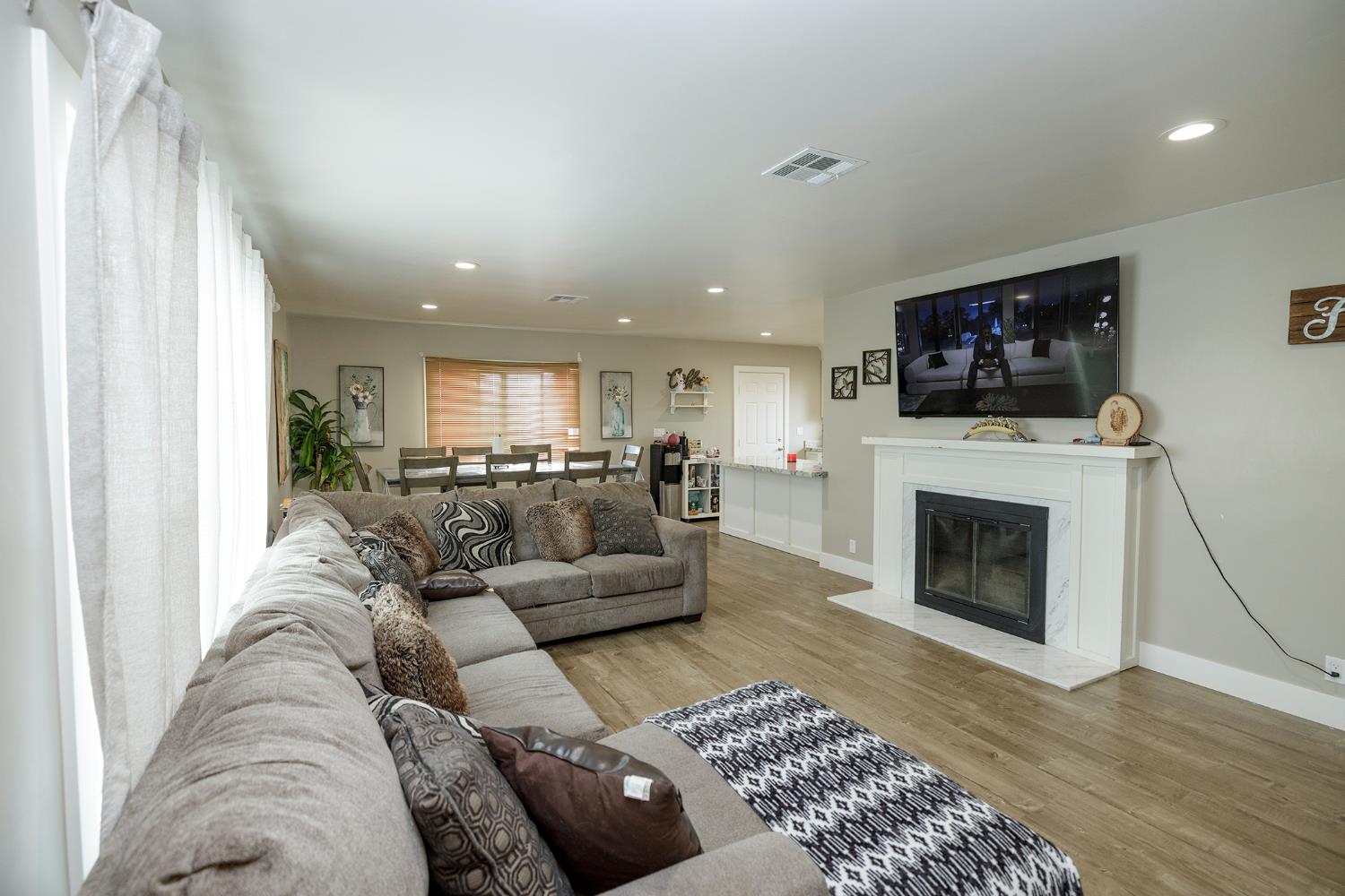 8712 Yosemite Boulevard Modesto, CA 95357 - Photo 6 of 24 a living room with furniture a fireplace and a flat screen tv