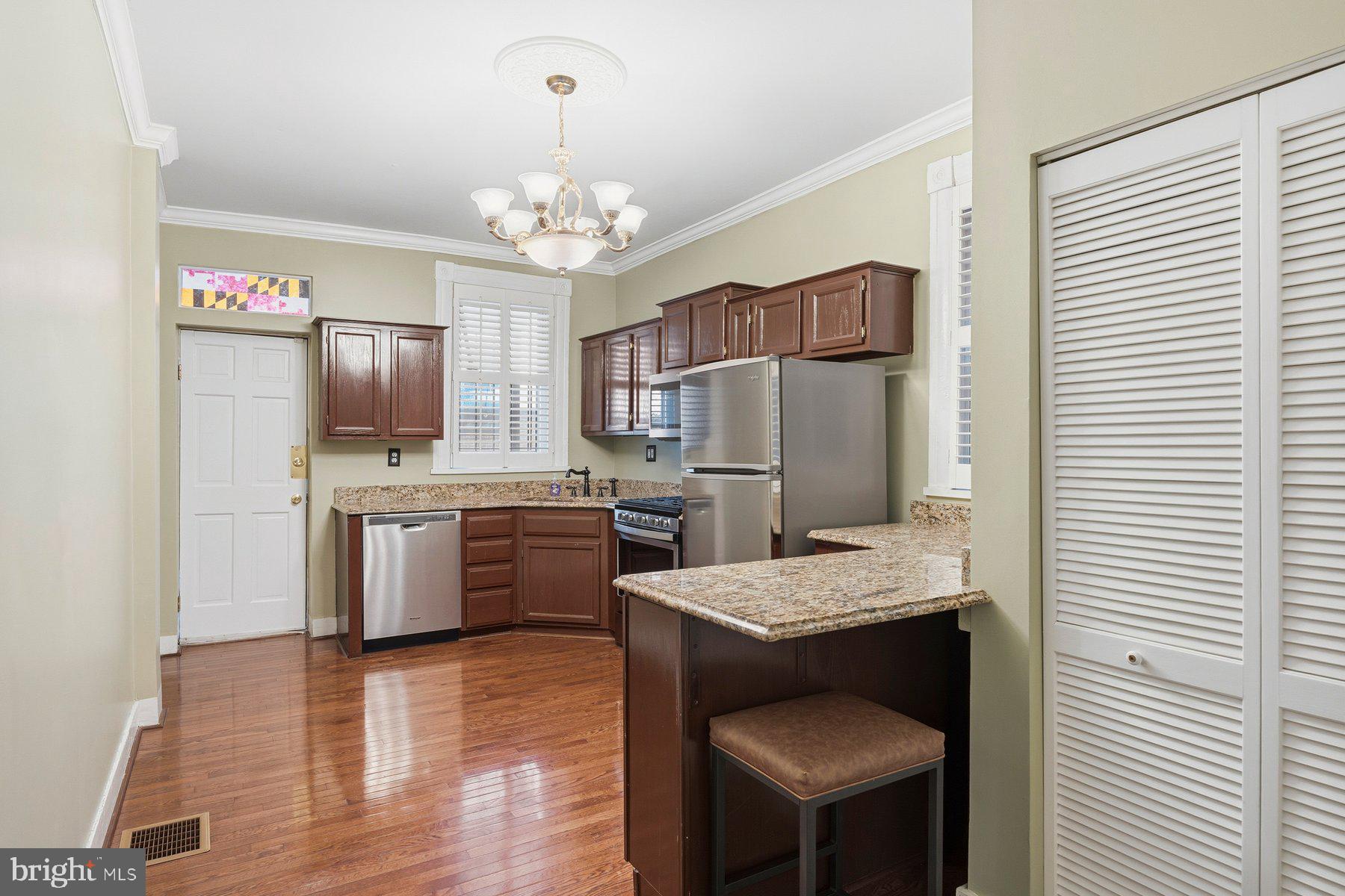 208 East Eager Street Baltimore, MD 21202 - Photo 10 of 31 a large kitchen with a refrigerator a stove a sink dishwasher a dining table and chairs with wooden floor