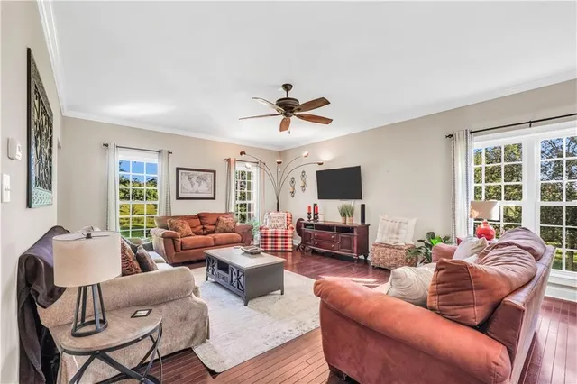 a living room with furniture a ceiling fan and a flat screen tv