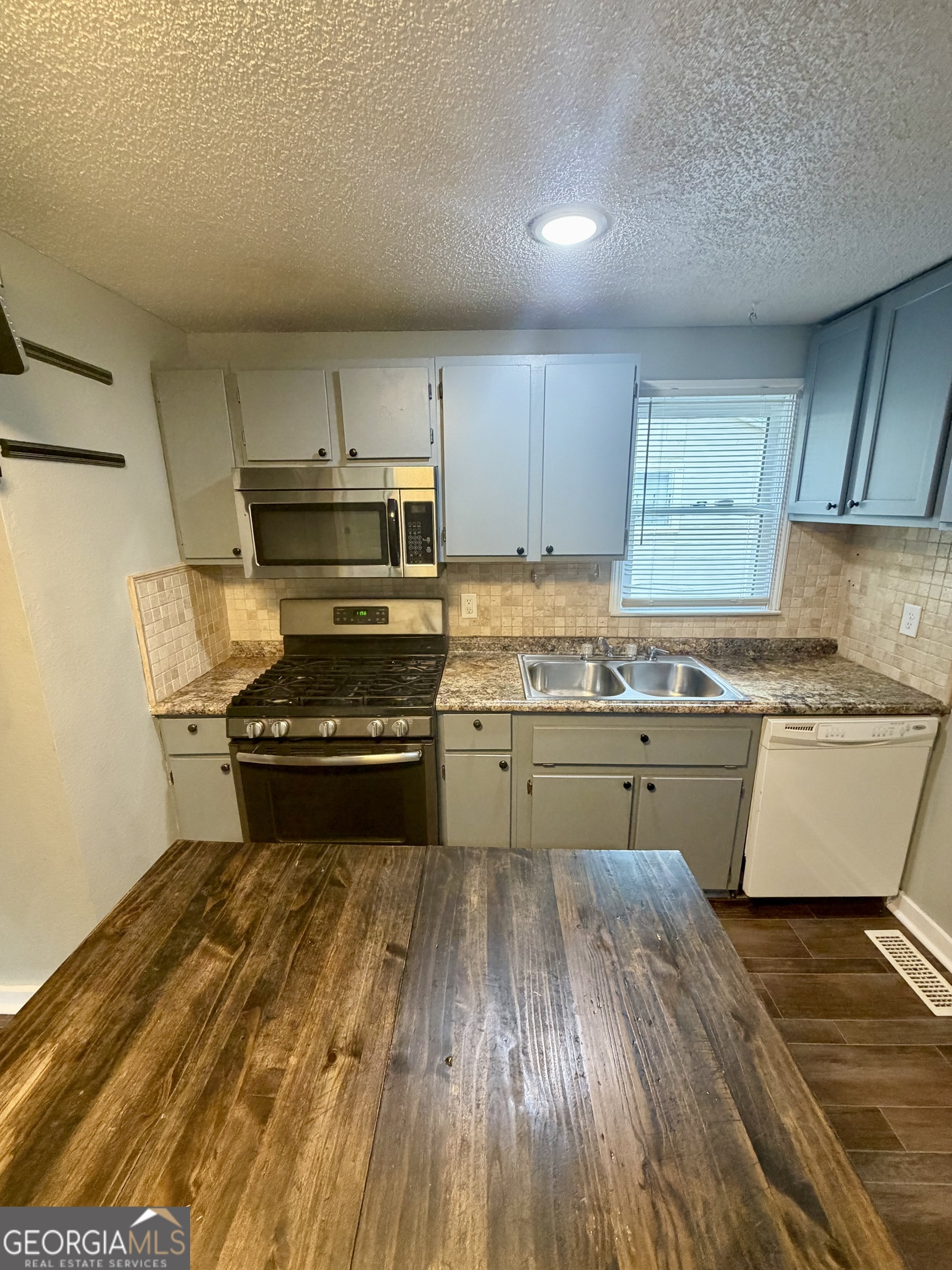 666 Woolfolk Street Macon, GA 31217 - Photo 30 of 60 a kitchen with kitchen island wooden floors appliances and cabinets