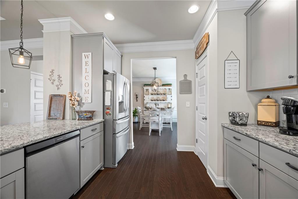2347 Persimmon Chase Monroe, GA 30656 - Photo 36 of 85 a kitchen with stainless steel appliances granite countertop a refrigerator a sink dishwasher and white cabinets with wooden floor