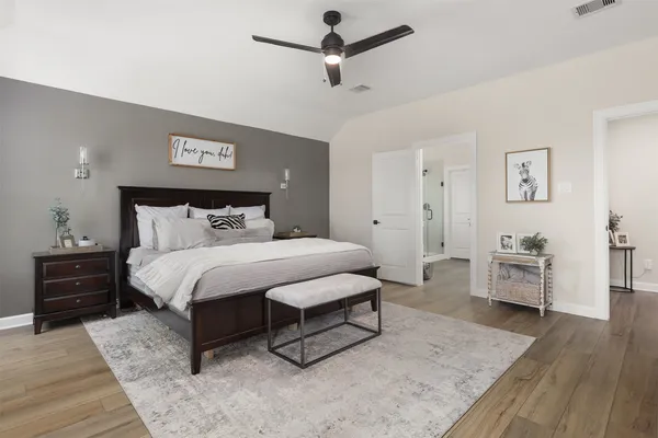 a spacious bedroom with a bed and wooden floor