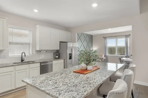 a kitchen with a granite countertop sink a stove a dining table and chairs