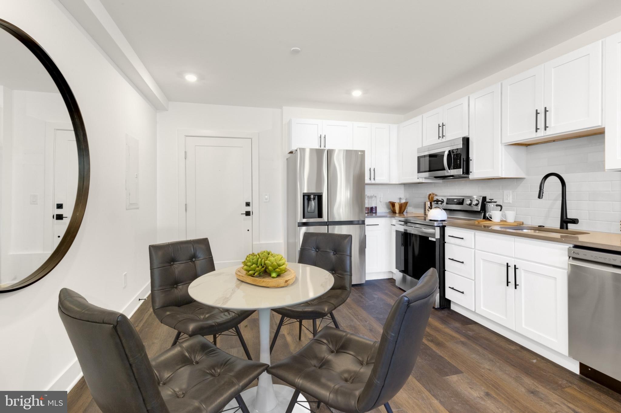 7037 Ridge Avenue, Unit 103 Philadelphia, PA 19128 - Photo 4 of 19 a kitchen with stainless steel appliances a dining table and chairs