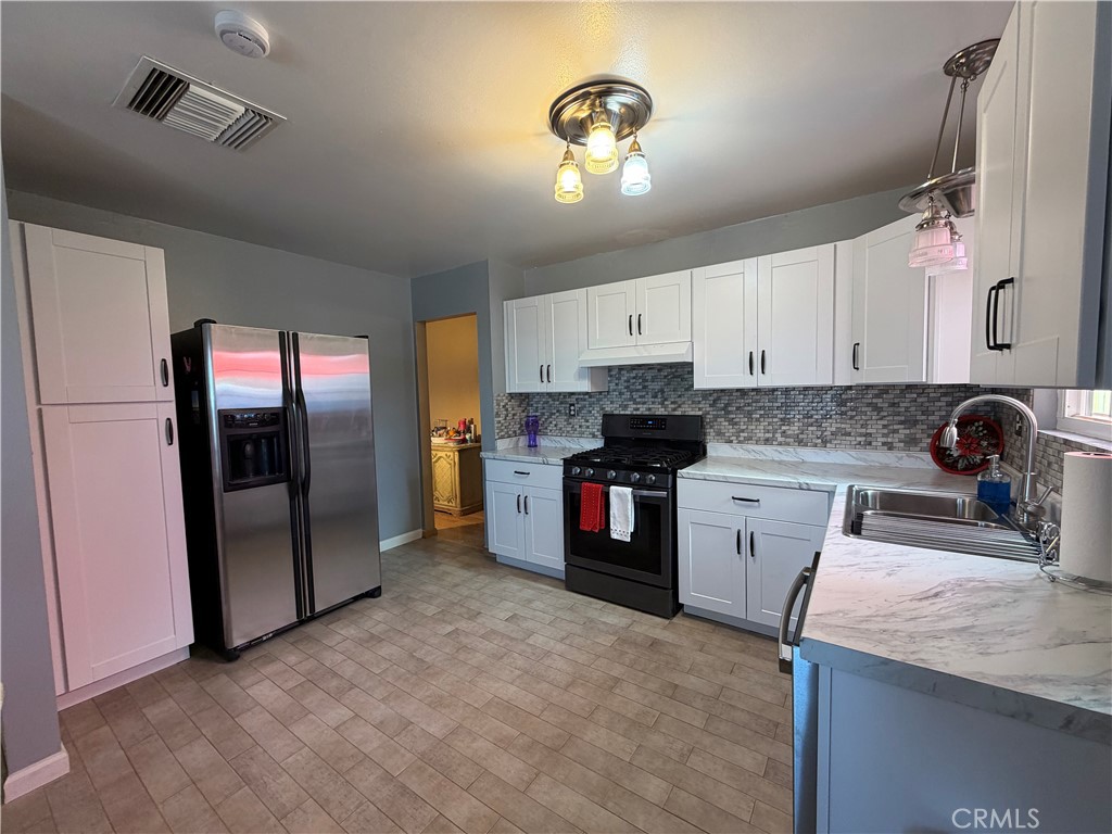 25478 Ash Road Barstow, CA 92311 - Photo 22 of 35 a kitchen with granite countertop a refrigerator and a stove top oven