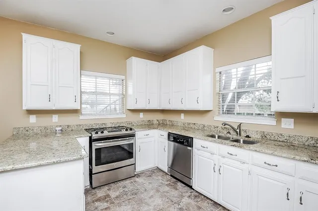 a kitchen with granite countertop stainless steel appliances white cabinets granite counter tops and a window