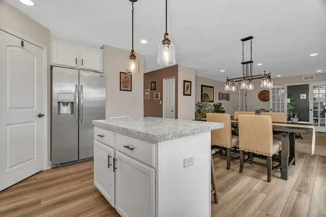 a kitchen with stainless steel appliances kitchen island granite countertop a table chairs and a wooden floor