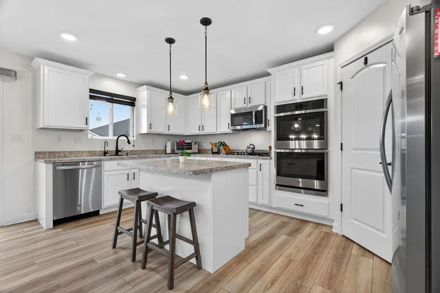 a kitchen with kitchen island granite countertop a sink a counter space stainless steel appliances and cabinets