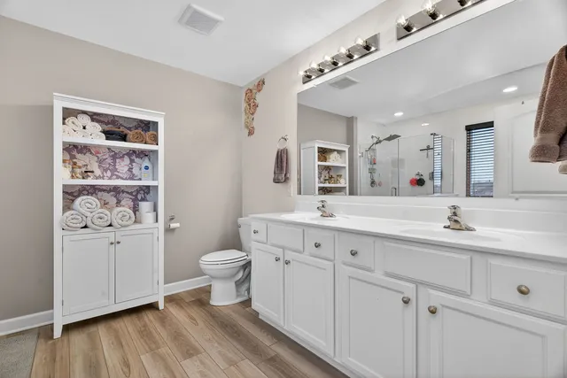 a spacious bathroom with a double vanity sink a toilet and a mirror