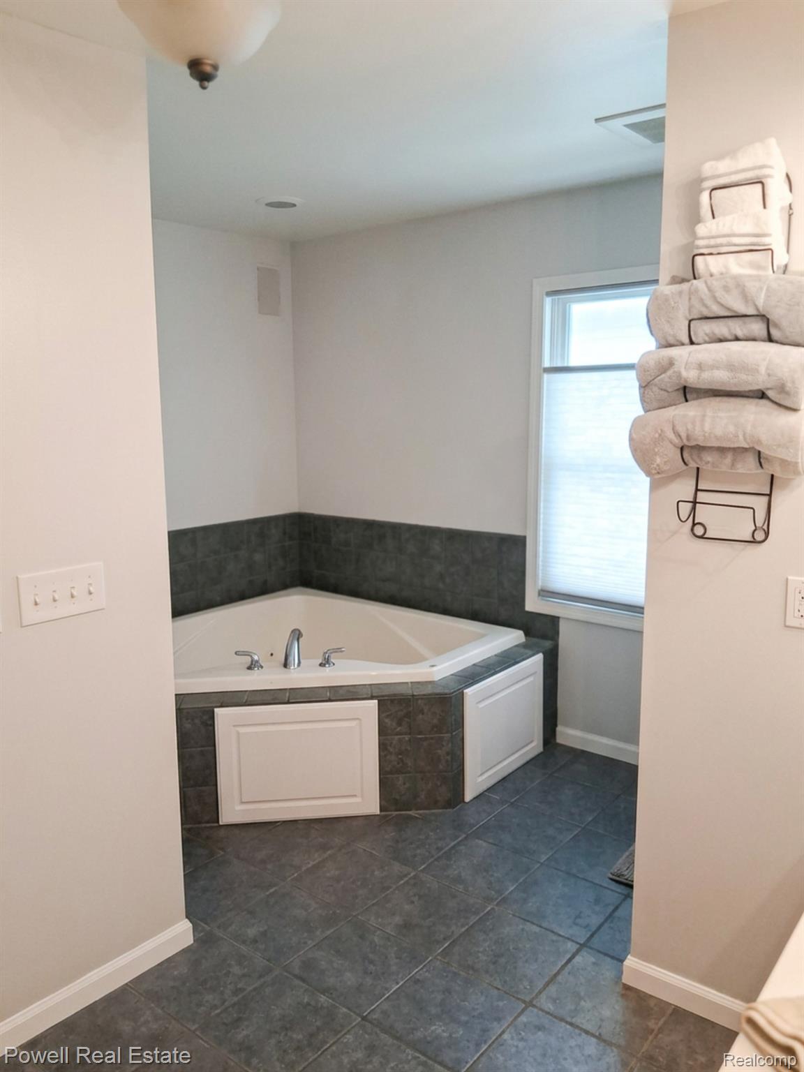 6807 Big Trail Road Holly, MI 48442 - Photo 21 of 45 Corner soaking tub with dark gray tile surround and white paneling