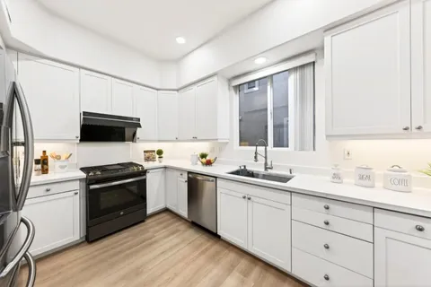 a large white kitchen with a sink and chairs