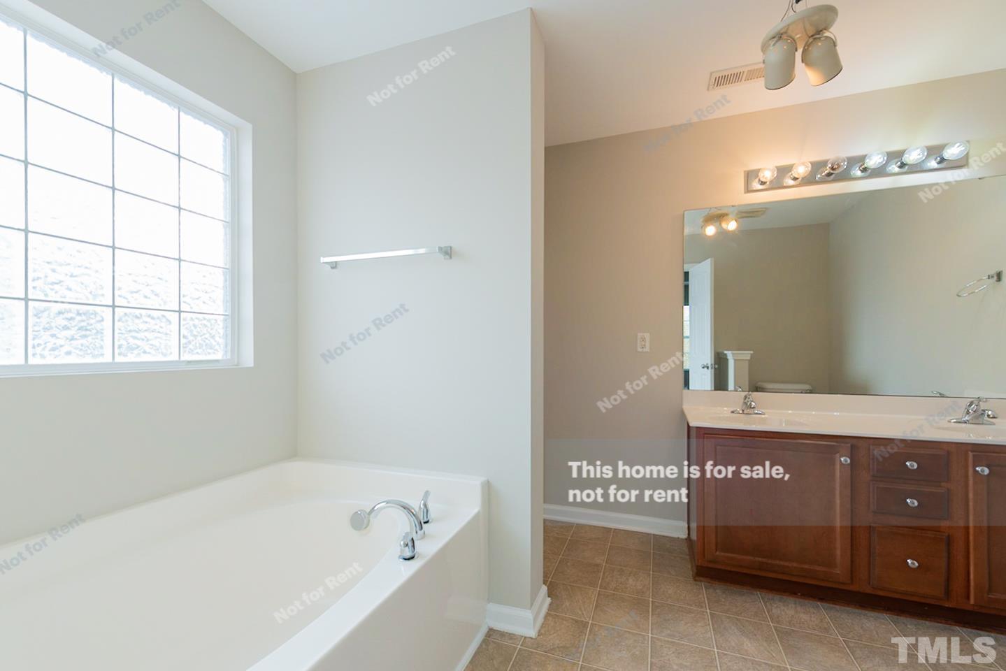 6328 Bunker Hill Drive Raleigh, NC 27610 - Photo 6 of 22 a bathroom with a tub a double vanity sink and mirror