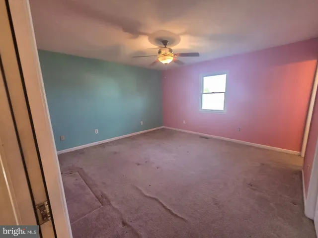 an empty room with a chandelier fan and windows