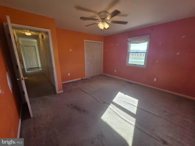 an empty room with windows and fan