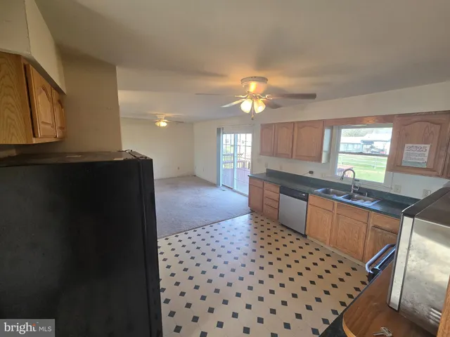 a kitchen with granite countertop a refrigerator a stove a sink and dishwasher with wooden floor