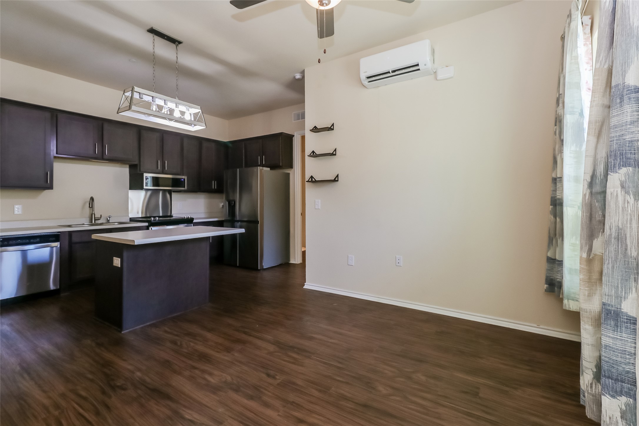 8601 West Gate Boulevard, Unit 7101 Austin, TX 78745 - Photo 6 of 16 Kitchen featuring light countertops, dark wood finish cabinetry, stainless steel appliances, a center island, and dark wood-style flooring